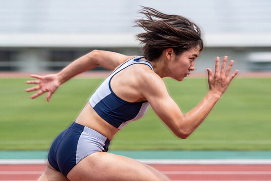 陸上競技場のトラックを全力で駆け抜ける女性アスリートの横顔