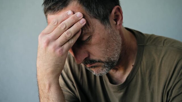 Middle-aged man suffering from headache and stress holding his temple in pain close-up portrait, 4K.