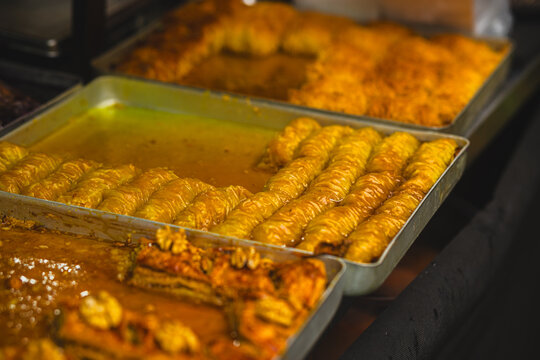 Traditional turkish baklava with honey syrup in metal trays on market counter. Sweet oriental dessert pastry with nuts. Middle eastern cuisine and street food concept for bakery and restaurant menu.