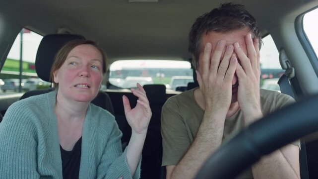 Frustrated couple in a car argue while stuck in traffic; the driver covers his face in stress as his partner gestures and speaks, showing tension, fatigue and relationship conflict on the road, 4K