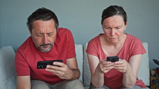 Man and woman checking mobile phones during serious conversation at home, woman hiding device screen from her husband, 4K