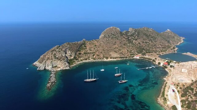 Yachts rest in a turquoise bay at Knidos, Datca, where rocky shores frame clear coastal water. Anchored sailboats and sheltered cove create a tranquil Aegean scene with charter travel appeal.