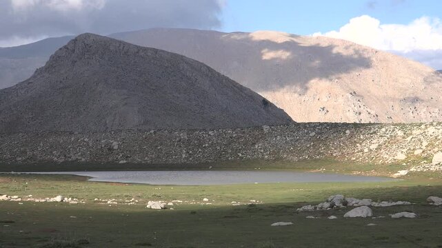 Peru mountain lake sits among treeless highland meadow and cold wetland terrain. Andean tundra, shoreline pools, and open grassland shape remote wilderness scenery.
