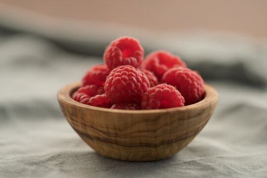 fresh ripe raspberries in a small wooden bowl