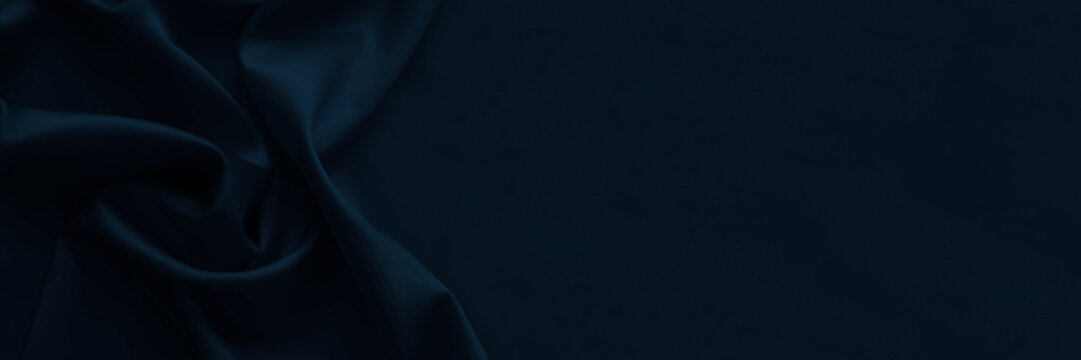 Black dark blue silk satin. Smooth silky shiny fabric material. Elegant background. Draped soft line fold. Gotic dramatic concept. Empty template design.Copy space.Table top view, flat lay.Wide banner