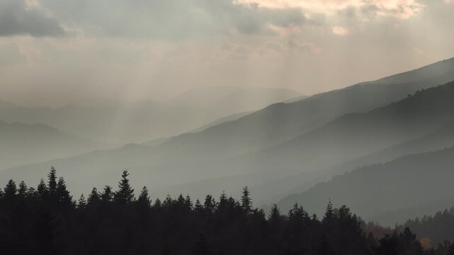 Fog fills a snowless valley, softening mountain slopes and creating a muted atmospheric view. Misty hills and layered ridges build a brooding landscape with subdued tones and open depth.