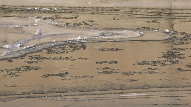 Partly frozen river carries slush and broken ice, revealing winter current across a cold channel. Floating floes drift through open water as seasonal thaw reshapes the frigid waterway below.