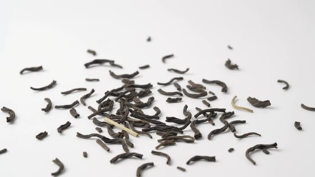 Dried black tea leaves scattered on white background. Loose organic tea infusion ingredients. Premium dark fermented tea for beverage marketing.