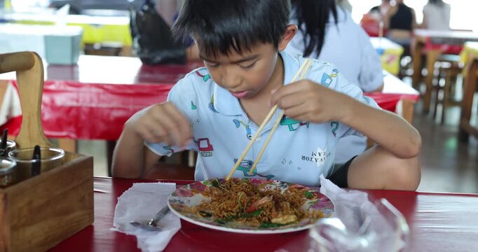 School kid boy enjoy eat food in traditional floating market travel in Thailand