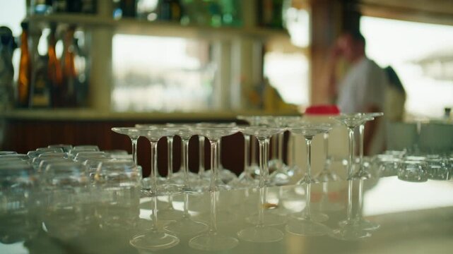 Close-up of empty wine and cocktail glasses on a bar counter with bottles behind, Cannes, France