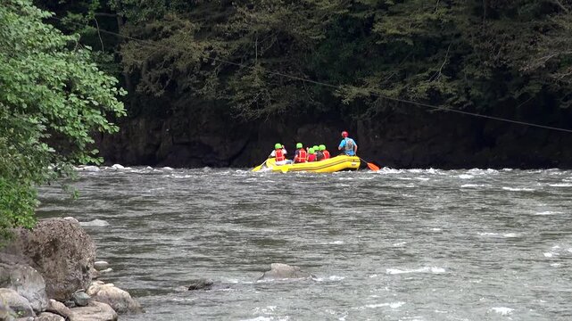 Yellow rafting boat charging through whitewater rapids on a fast river during adventure trip. Inflatable raft, wild stream, paddling sport, rushing current, outdoor excursion action.
