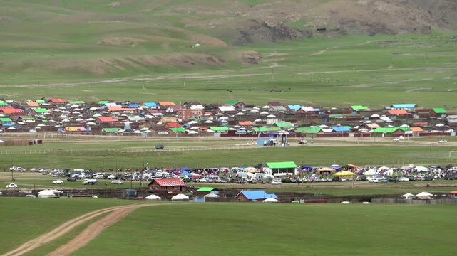 Panoramic view of Mongolian residential zone showing mixed urban rural buildings across open steppe. Dwellings spread plains, community layout, roadside pattern, prairie settlement.