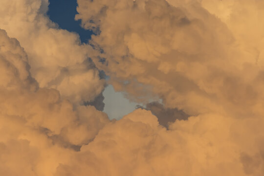 Primer plano de nubes aborregadas con un peque&ntilde;o claro de cielo azul. La luz c&aacute;lida resalta las texturas suaves y dram&aacute;ticas del cielo.