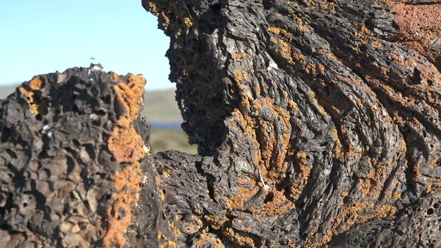 Frozen basalt lava rocks show porous vesicular texture formed by ancient volcanic activity. Geologic closeup reveals trapped gas cavities within solidified magma stone, rough surface.