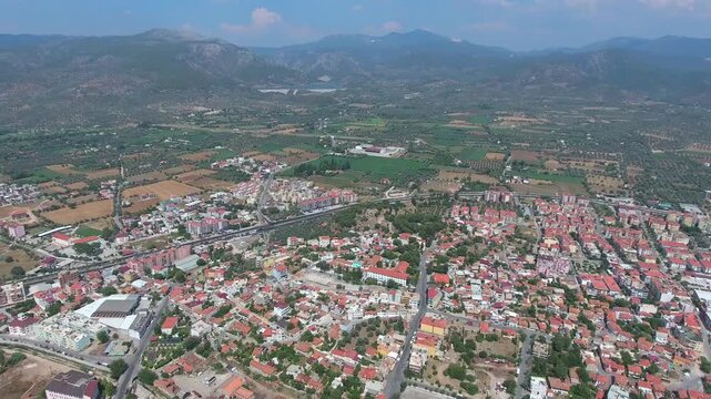 Aerial view shows traditional Milas town in Mugla with sunny roofs and historic houses. Anatolian settlement narrow streets reflect authentic urban heritage across summer terrain.