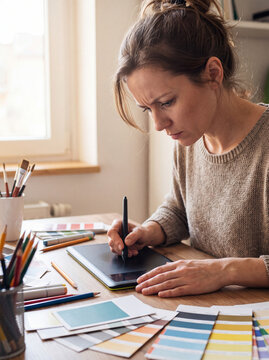 Focused Female Graphic Designer Using Digital Drawing Tablet with Color Swatches