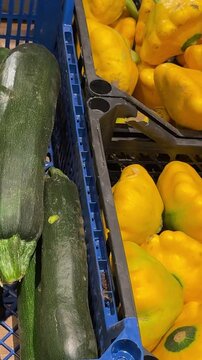 Fresh yellow pattypan squash and dark green zucchini arranged in neighboring wooden crates create a colorful vegetable display for markets, grocery stores and everyday shopping. Close up.