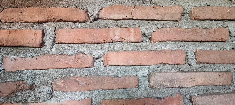 Weathered red brick wall with rough gray mortar