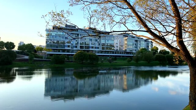 Residential complex to lake on sunset. Landscape with multifamily home near lake. Real estate investment landscape. Apartment complexes, condo buildings.   Multifamily properties.