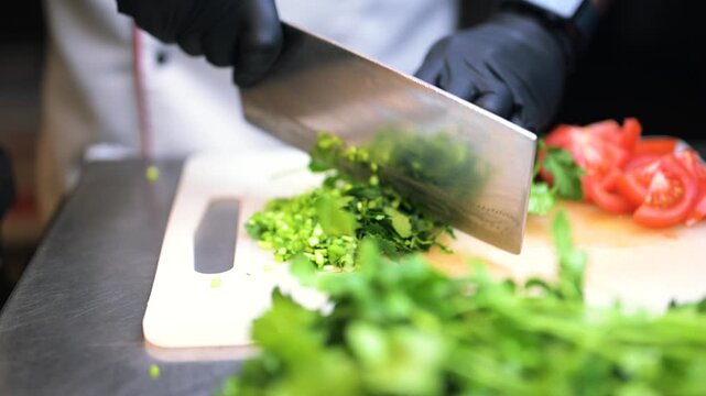 A professional chef is chopping coriander on a chopping board. 4K close up view of fresh coriander and tomato.