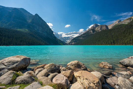 Lake Louise summer landscape with tourists canoeing on turquoise water under Victoria Glacier. Banff, Alberta, Canada.