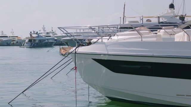 Close-up of a yacht's bow with mooring lines among moored superyachts in a marina, Golfe-Juan, France