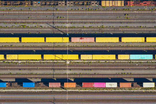 Aerial view of colorful freight train cars parked on parallel tracks in the industrial rail yard of La Spezia, Liguria, Italy.