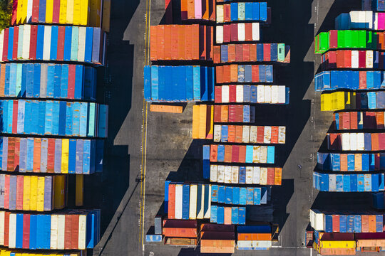 Aerial view of colorful shipping containers stacked in neat rows at the industrial port terminal in La Spezia, Liguria, Italy.