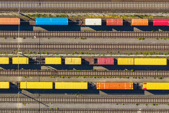 Aerial view of colorful freight train cars parked on parallel tracks in a railway yard in La Spezia, Liguria, Italy.