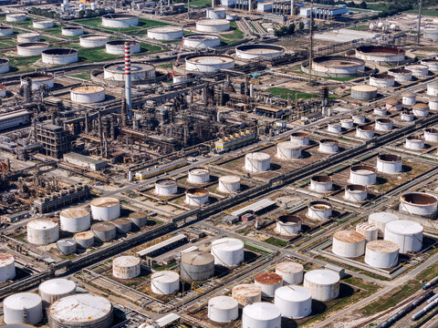 Aerial view of the Eni Sannazzaro Refinery, featuring numerous large storage tanks, industrial infrastructure, and processing units in Sannazzaro de' Burgondi, Lombardy, Italy.
