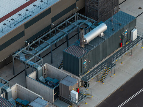 Aerial view of data center power backup and cooling systems featuring industrial containers, metal walkways, and concrete enclosures in Poland.