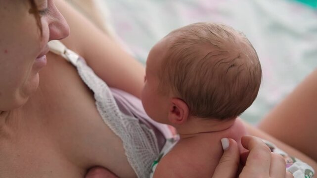 Young mother gently holding her newborn baby in her arms after feeding, sharing a tender moment of closeness and maternal care, highlighting the loving bond between mother and child