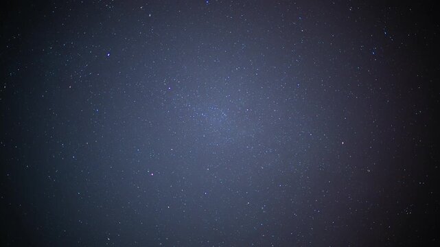 Timelapse of a starry night sky with a faint satellite trail