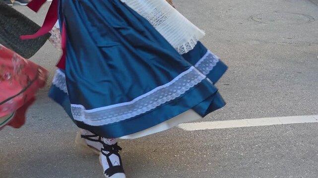 Close-up of a dancer in a traditional floral print dress with green ribbon and embroidered apron during a folk dance at the grape harvest festival in Teulada, Spain