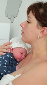 Caring mother holding her newborn child close to her chest, gently soothing and calming the crying infant with love and tenderness in a bright room, showcasing the strong bond of motherhood