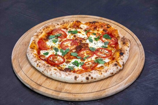 Freshly Baked Pizza with Tomato and Mozzarella on Wooden Board