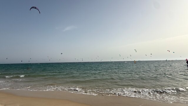 Kitesurfing at Valdevaqueros beach Tarifa Cadiz Spain, many kitesurfers with colorful kites in turquoise sea, windy beach paradise for water sports
