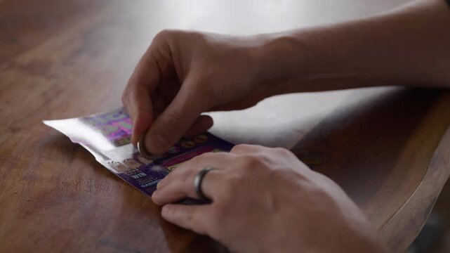 Man scratches lotto ticket - isolated shot of hands - hyperlapse