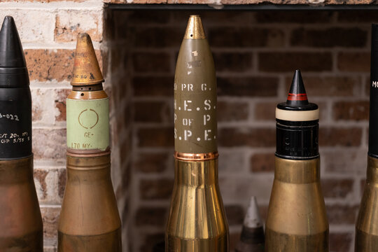 Large vintage military tank shells displayed against a brick wall