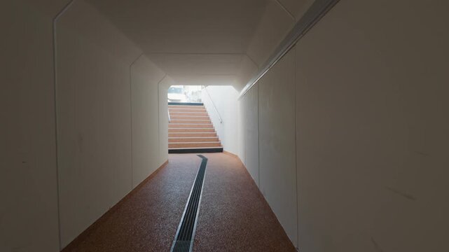A pedestrian underpass with pink flooring leading up a staircase to street level, Cote d'Azur, France