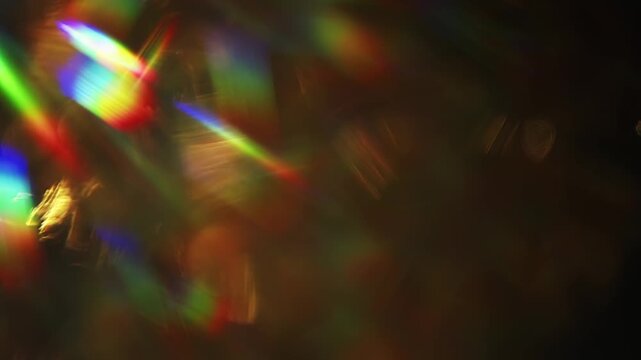 Dreamy bokeh of a golden shimmer and dazzling rainbow rays. Real optical effect of shining gold creating an aura of luxury and a visual of glamorous glittering lights and sparkling reflections. Loop.