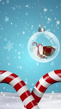 Animation of snowflakes falling over hanging snowglobes and candy cane on winter landscape