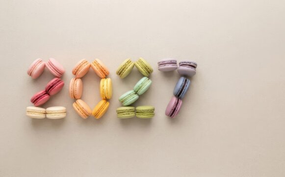 2027 New Year greeting made of colorful sweet macarons on neutral beige background, creative pastry food concept for calendar cover design and holiday celebration banner