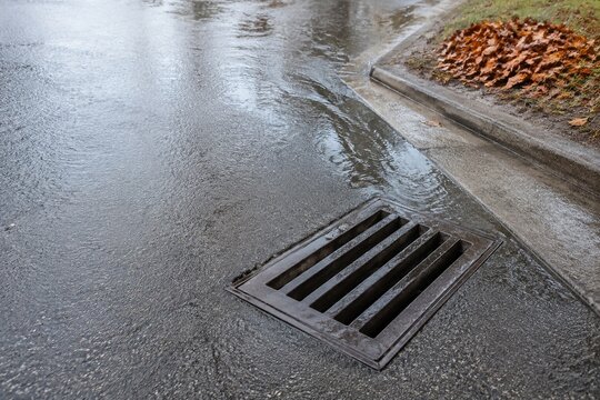 Cleared storm drain beside autumn leaves before heavy rain