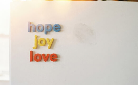 Magnetic words hope joy and love spelling positive emotions on a white refrigerator door representing inspiration and motivation