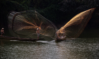 Throwing a fishing net on Nhu Y river, Hue, Vietnam. This is a river flowing through Hue city, where many Hue fishermen live.  © huong