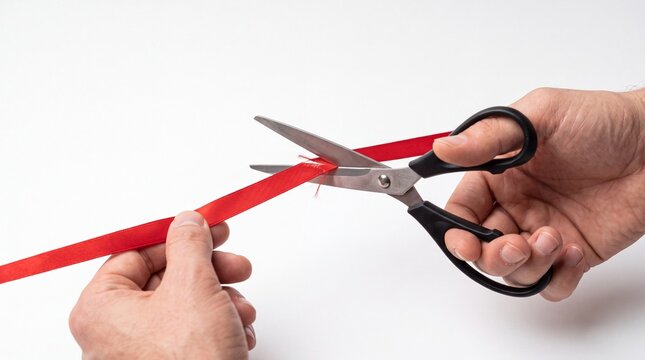 A close-up shot shows a pair of hands holding a red ribbon and a pair of scissors to cut it.