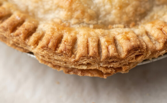 Close up of flaky pie crust with crimped edges on baked apple pie dessert ready for holiday celebration