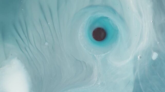 Abstract swirling liquid marble paint mixture creating hypnotic eye pattern.