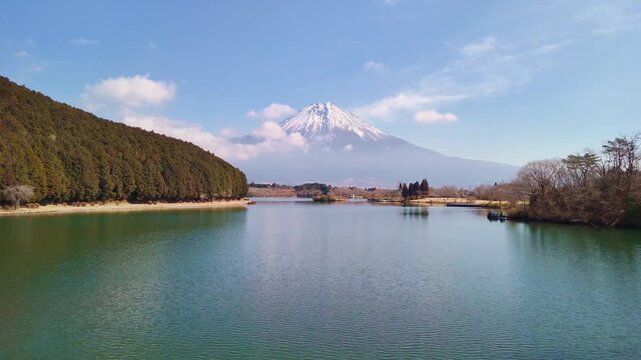 Aerial view of majestic mount fuji reflecting on calm tanuki lake water surface during sunny winter morning in japan.